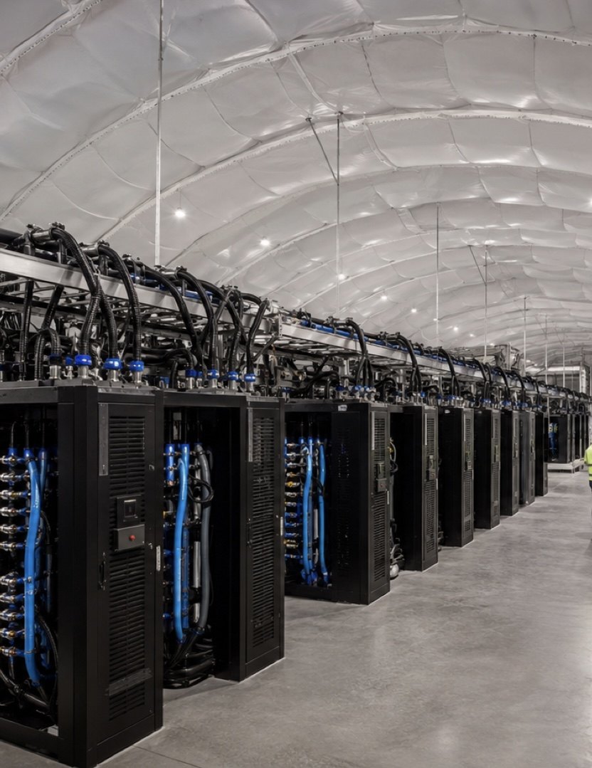 Interior of an existing air-dome installation showing high-density racks with liquid cooling distribution beneath the fabric enclosure